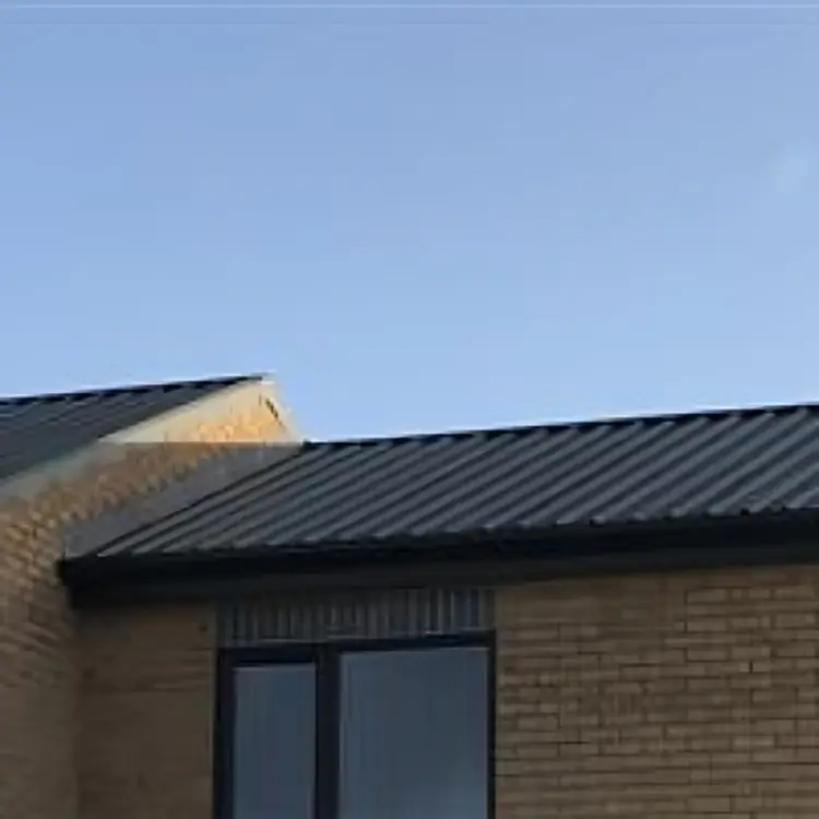 New anthracite profiled metal roof sheets and gutters on a buff-brick building