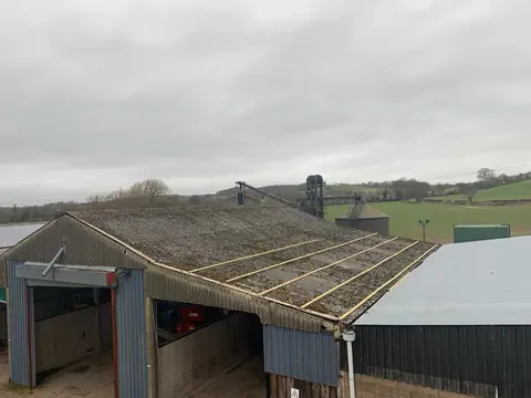 Timber battens fixed across an aged corrugated cement roof on a farm building, ready for overcladding